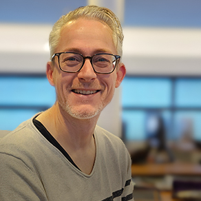 Portret van een glimlachende man met bril in een kantooromgeving