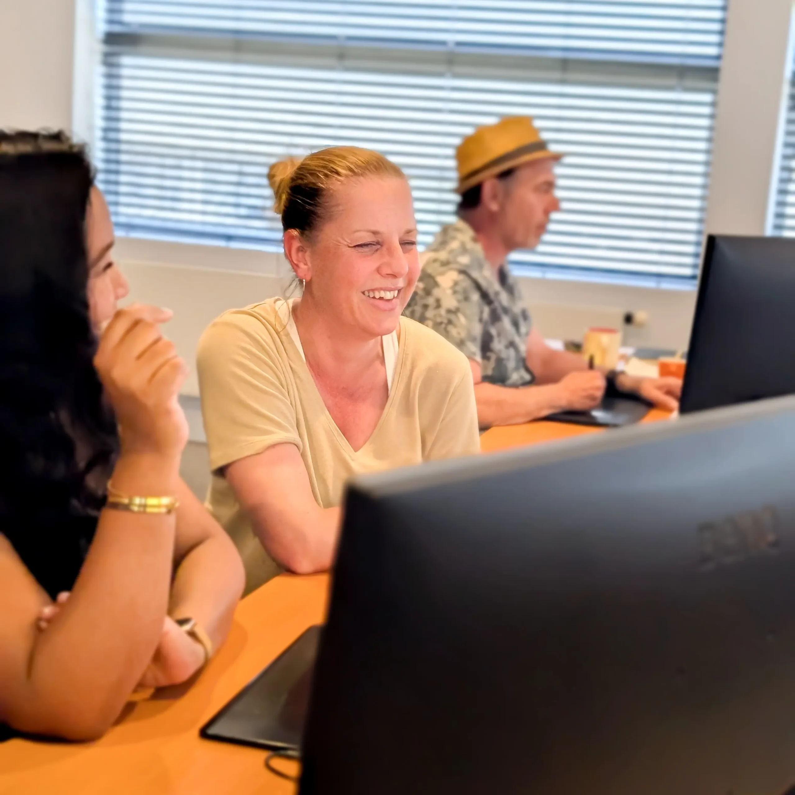 Collega’s lachen samen tijdens een vergadering aan een tafel met laptops