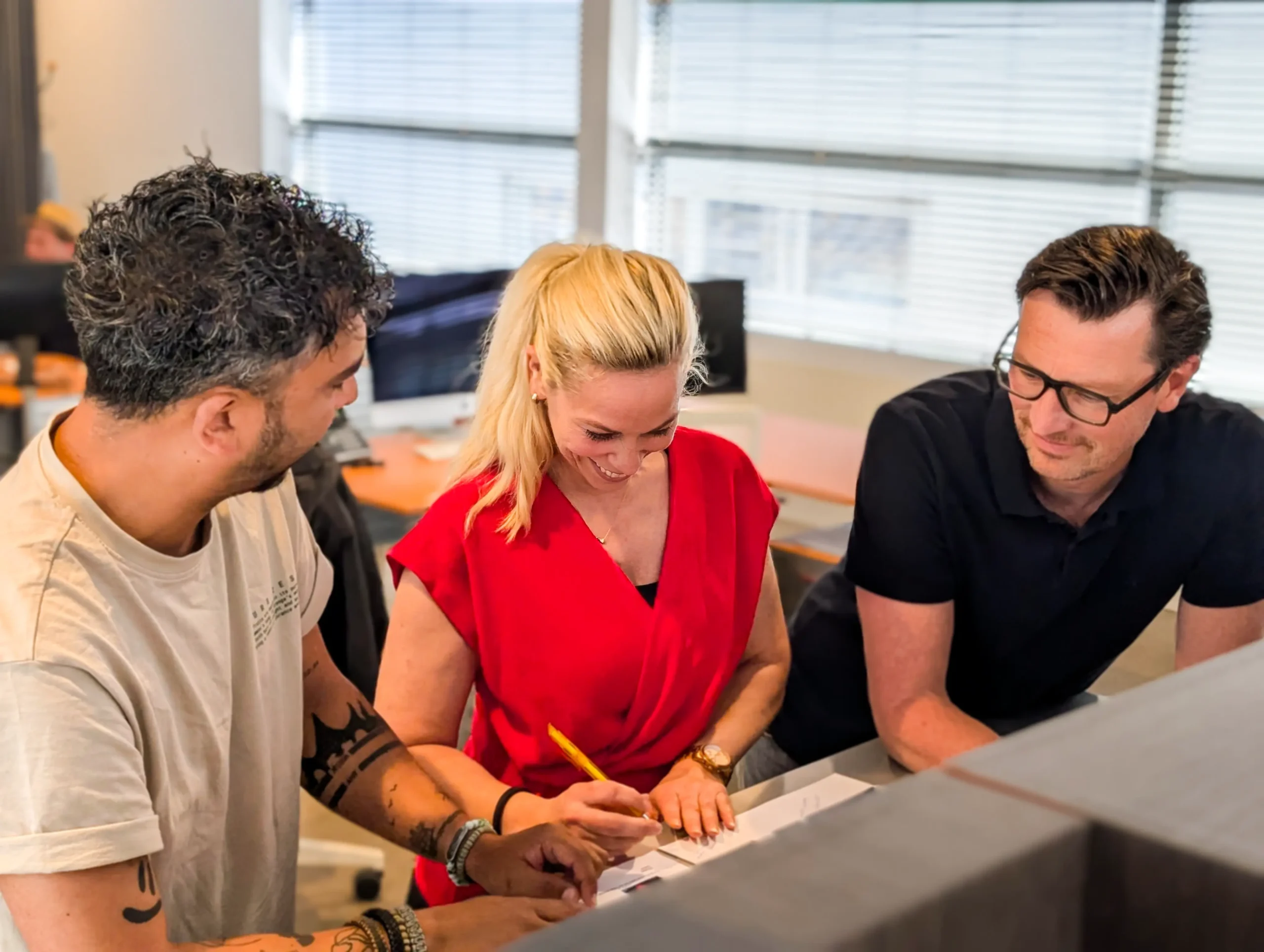 Drie collega’s overleggen en schrijven samen aan een document op kantoor