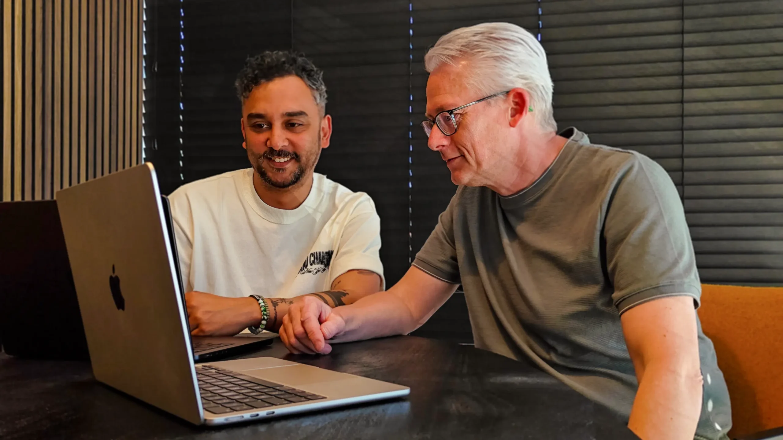 Twee mannen kijken samen naar een laptop aan tafel